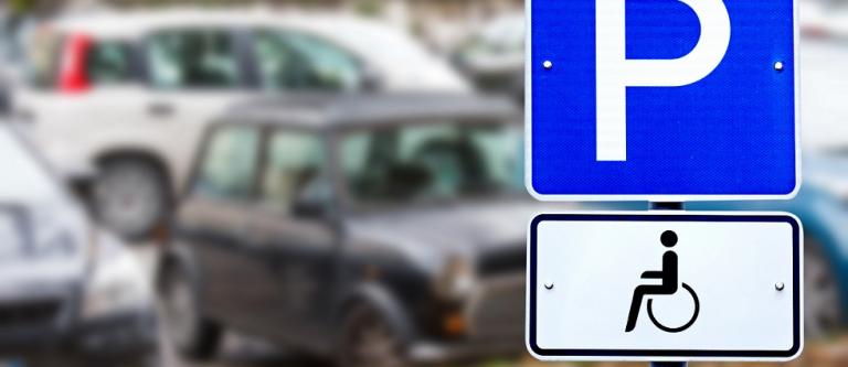 Disabled,Parking,Sign,Over,Blurred,Street,City,Background.