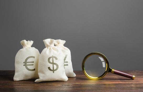 Three,Bags,Of,Money,And,A,Magnifying,Glass.,Search,For