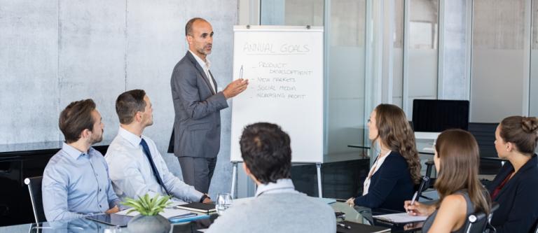 Confident,Mature,Businessman,Giving,A,Presentation,To,His,Team,In
